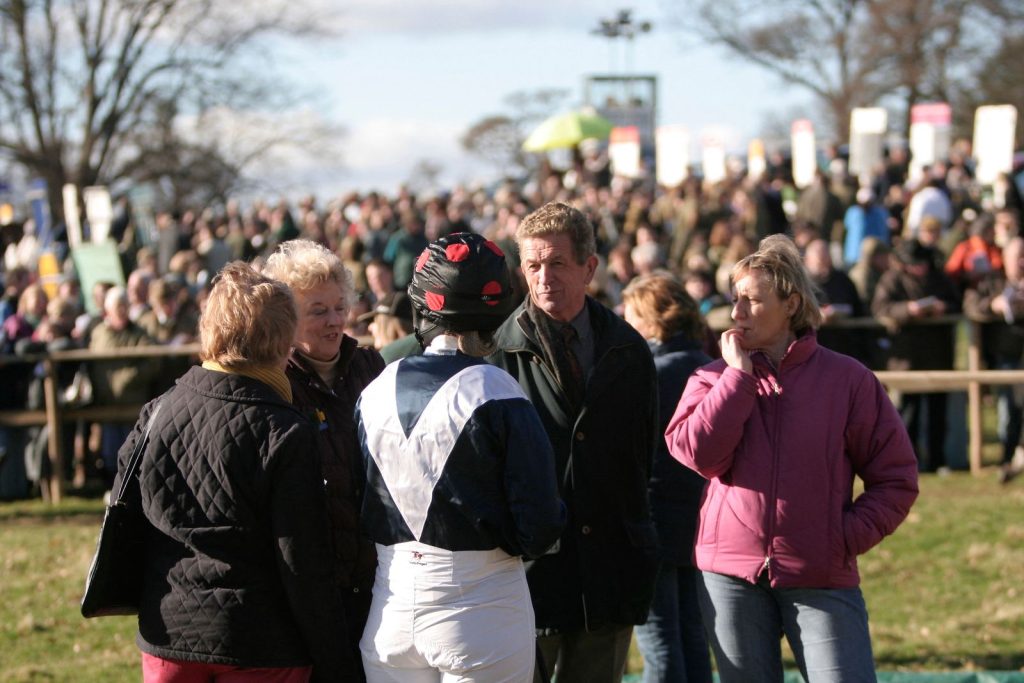 A trainer talking with owners in the parade ring before a race